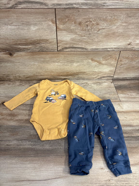 Yellow construction vehicle baby bodysuit with matching blue pants set on wood background