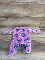 Flat-lay of pink plush Lilo & Stitch footed sleeper showing all-over Stitch print and built-in footies on a wood floor
