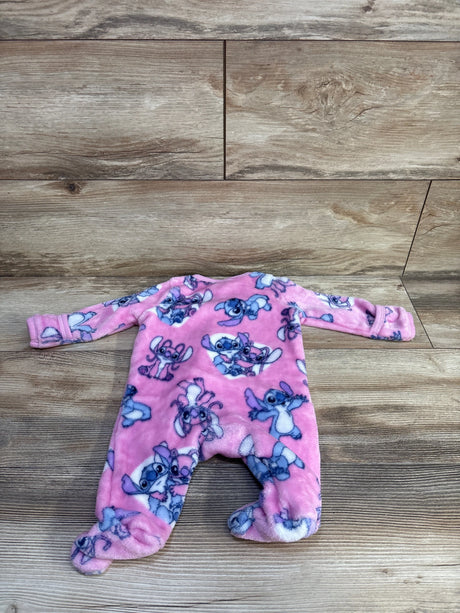 Flat-lay of pink plush Lilo & Stitch footed sleeper showing all-over Stitch print and built-in footies on a wood floor