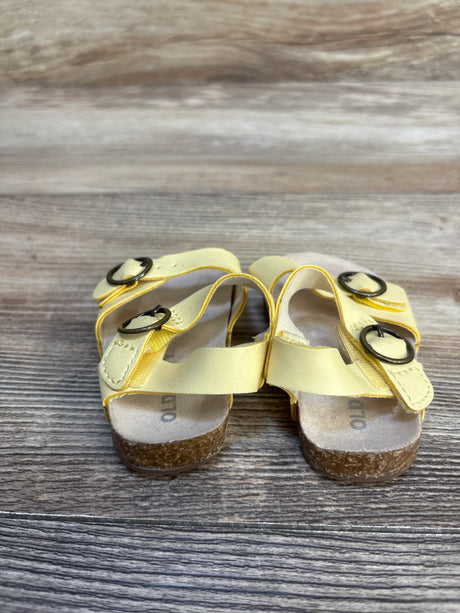 Yellow toddler sandals with buckled straps on wood floor