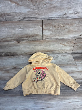 Beige kids hoodie with unicorn and pizza graphic, Amore Mio text, on wood background.