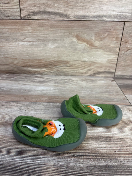 Angled view of green knitted baby sock shoe size 3C showing giraffe face and gray rubber sole on wood floor