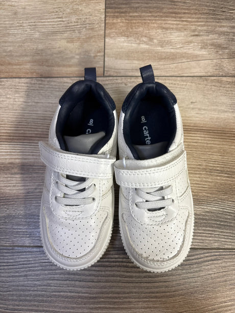 Top-down view of Carter's Every Step sneakers, white size 8C, showing perforated toe, Velcro strap, navy heel on wood floor