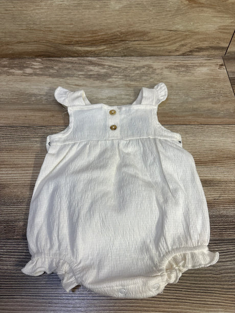 Flat lay of Nicole Miller ivory romper 0-3mo with ruffled straps, wood buttons, ruffled leg openings and snap crotch on wood