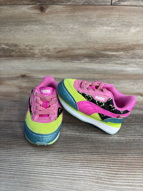 Pair of colorful Puma kids running shoes with pink, yellow, teal, and black design on wooden floor