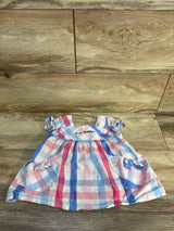 Baby dress with pink and blue plaid pattern, short sleeves, and bow accents on wood floor