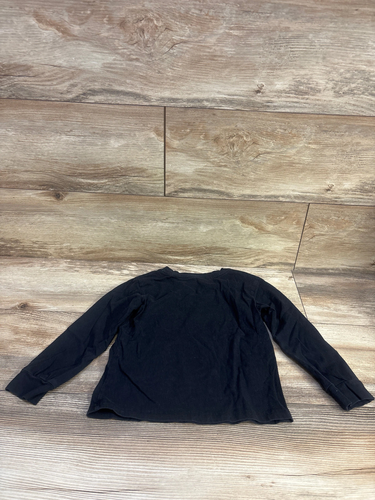 Back view of black Marvel The Punisher long sleeve shirt in size 3T showing its plain back on wood flooring