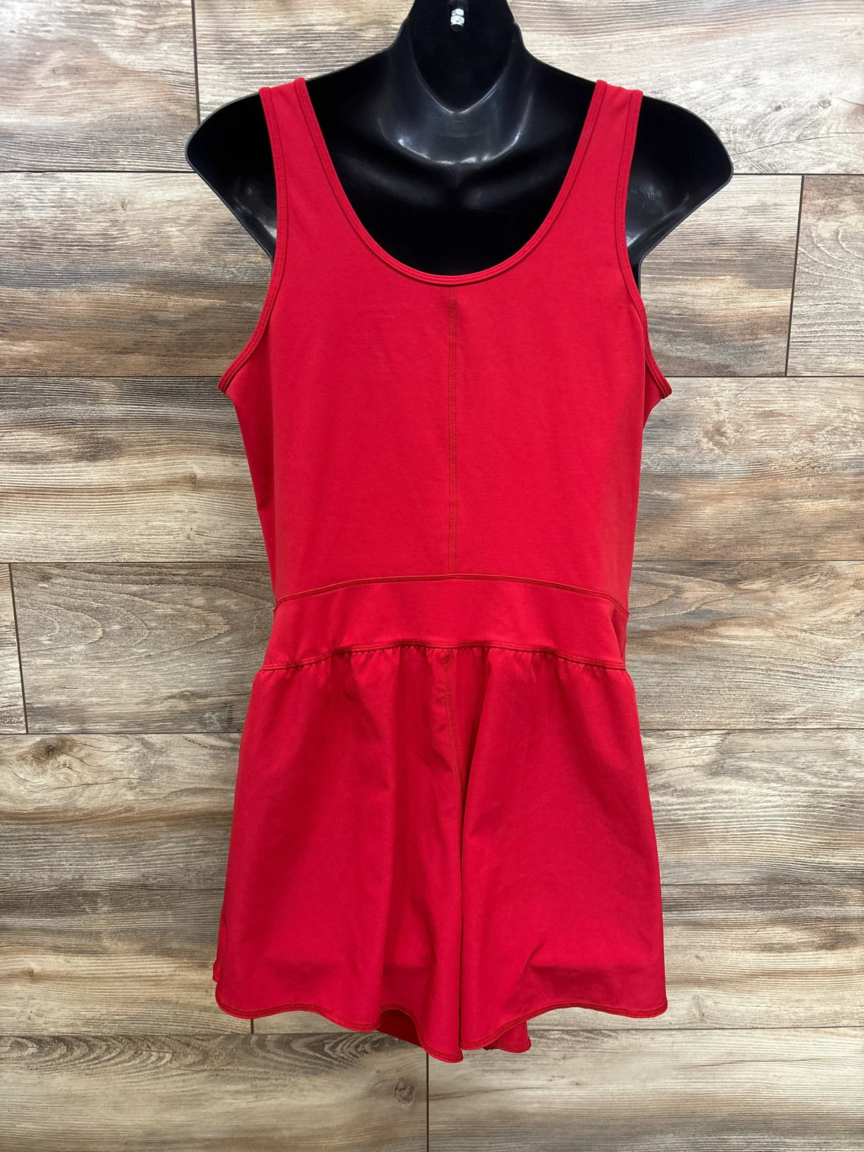 Front view of red Isabel maternity romper on black mannequin showing scoop neckline, gathered waist and shorts against wood background