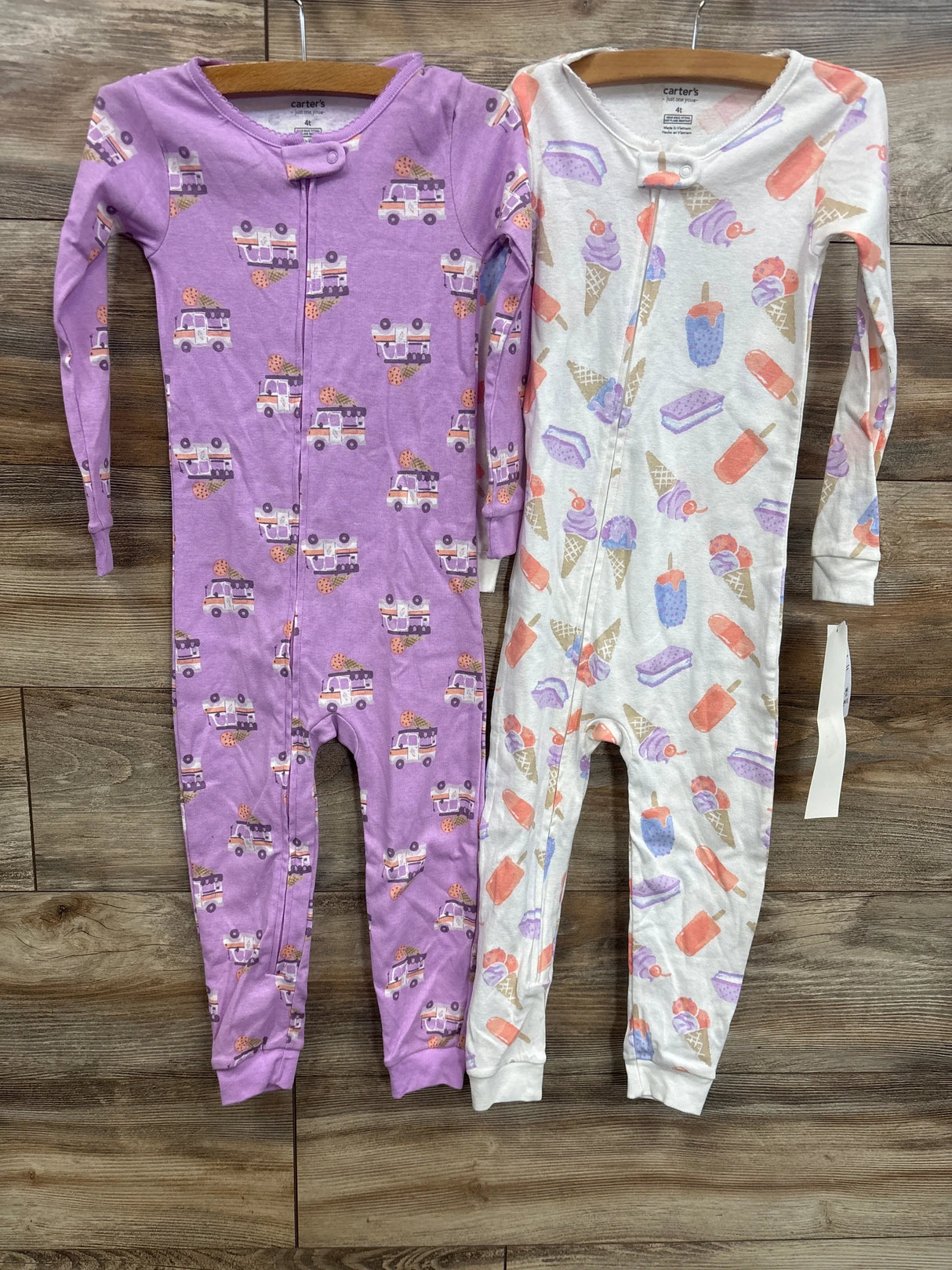 Two long sleeve baby sleepers, one purple with ice cream trucks, one white with dessert prints.