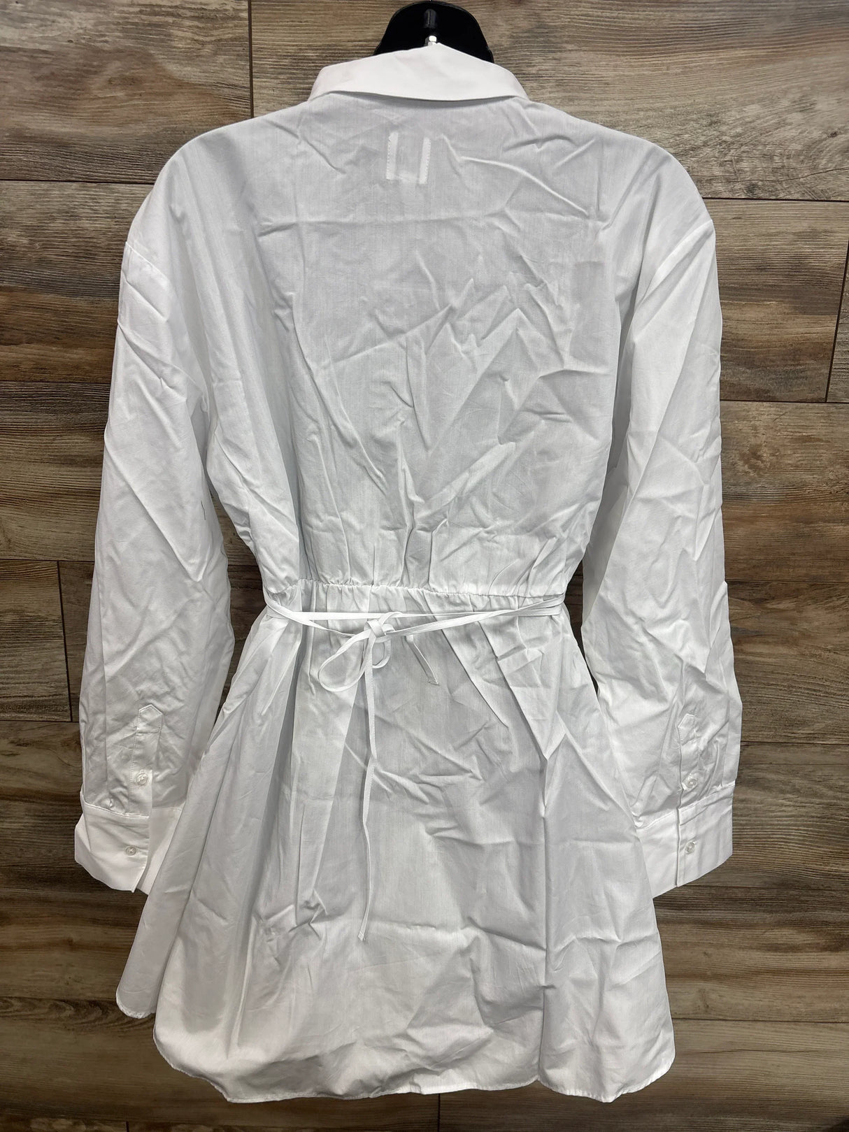 White maternity shirt dress with tie waist, long sleeves, and button cuffs on mannequin