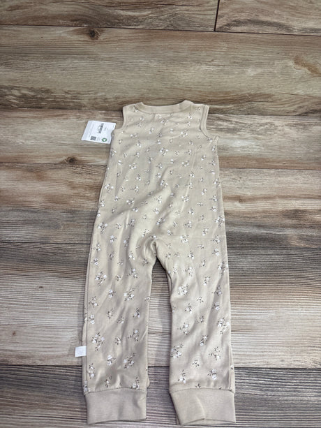 Front view of tan Little Planet sleeveless Henley jumpsuit showcasing floral print and cuffed ankles on a wood background