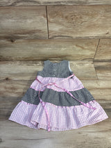 Flat lay of Rare Too! seersucker gingham dress with black-and-white and pink tiered panels and pink sash on wood floor