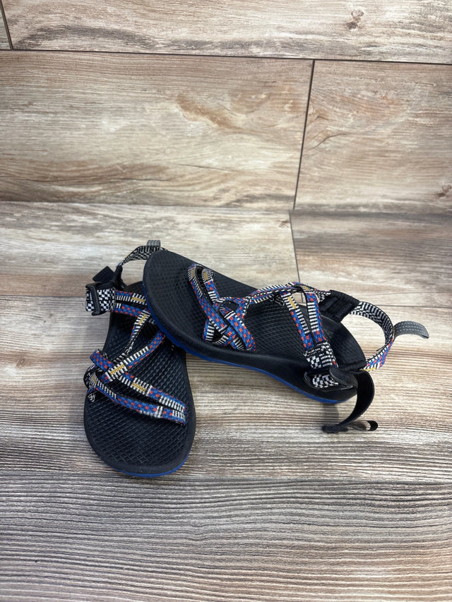 Top-front view of Chaco ZX1 Ecotread toddler sandals in black with multicolor webbing straps, textured footbed, and adjustable ankle strap on wood backdrop, size 13C