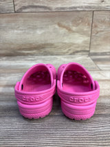 Rear view of pink Crocs Classic Clog, size 9C, showcasing heel strap and embossed Crocs logo on wood floor background