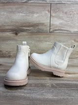 Front and side view of Cat and Jack beige toddler Chelsea boots showing pebbled faux leather, elastic side panels and pink soles on wood floor