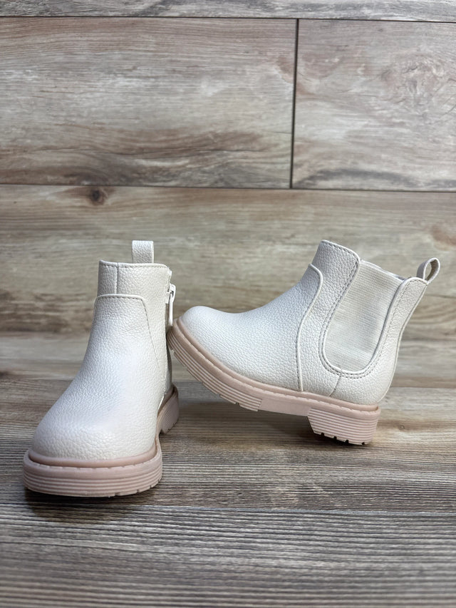 Front and side view of Cat and Jack beige toddler Chelsea boots showing pebbled faux leather, elastic side panels and pink soles on wood floor