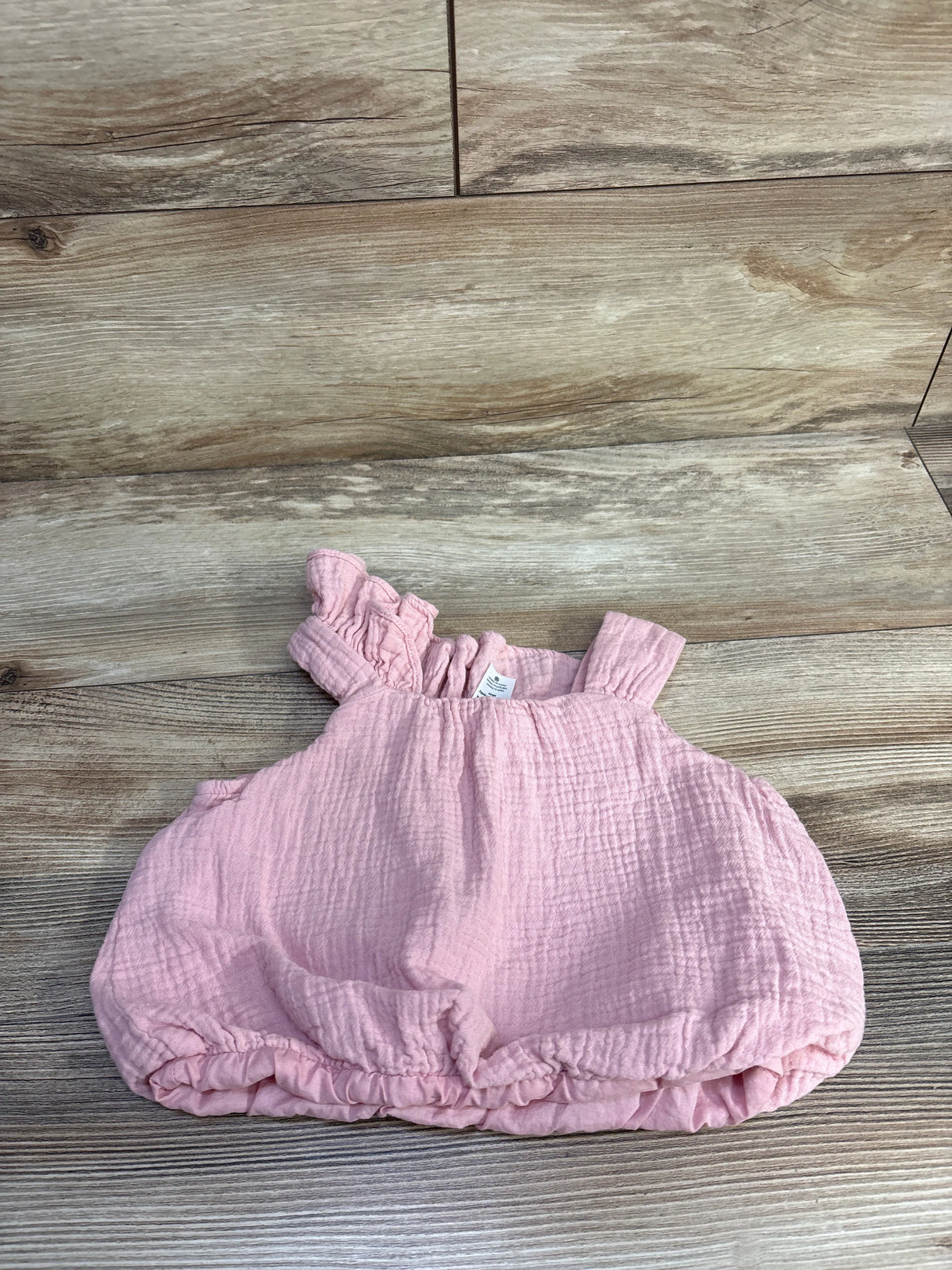 Top-down view of pink Carter's gauze toddler top (3T) showcasing ruffled shoulder strap and elasticized hem on a wood plank background