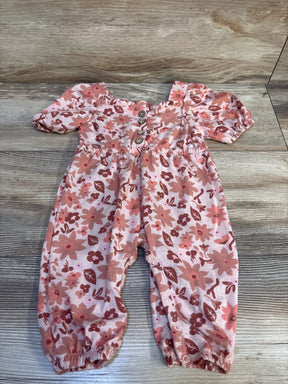 Pink floral long-sleeve baby romper with front buttons, displayed on wood floor