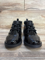 Black patent leather toddler dress shoes with laces and side zippers on wood floor