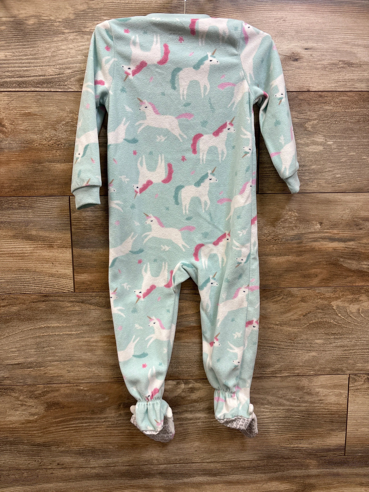 Front view of Carter’s blue blanket sleeper in size 2T showcasing long sleeves, footed legs, and unicorn print on a wood background