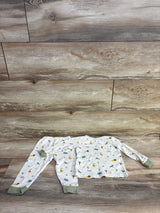 Top-down view of Mori Baby two-piece ivory safari pajama set (9–12 months) showing long-sleeve top and pants with green cuffs and animal print on wood background