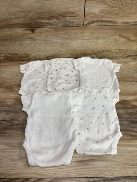 Top-down view of Next Baby five-piece white bodysuit set in assorted prints, newborn size, on a wood floor