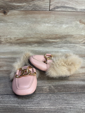 Pink leather slippers with beige fur lining and gold chain decoration on wooden floor