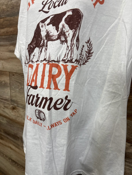 Side view of white maternity T shirt showing front print Support Your Local Dairy Farmer with cow illustration on wood background