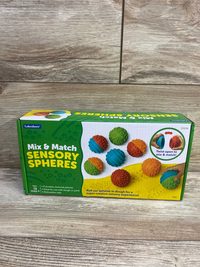 Front view of Lakeshore Mix & Match Sensory Spheres box showcasing colorful textured balls and twist-open mix feature on a wood floor background