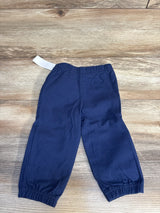 Navy blue kids joggers with elastic waist and cuffs, laid flat on wood floor