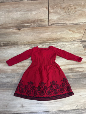 Red long sleeve toddler dress with black floral embroidery on skirt, laid flat on wooden floor