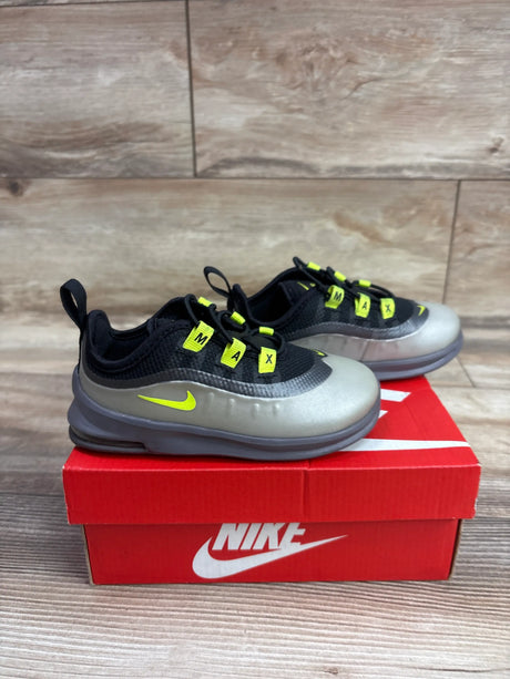 Three-quarter view of Nike Air Max Axis TD Black Volt sneakers showcasing black mesh, gray overlays, and neon yellow accents on a red Nike shoebox