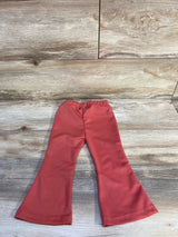 Flat lay of red toddler flared pants showing elastic waistband and wide flared legs on wood background