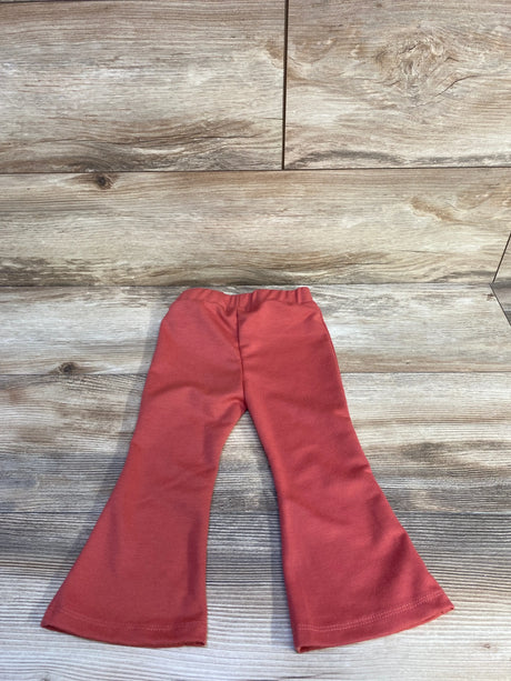 Flat lay of red toddler flared pants showing elastic waistband and wide flared legs on wood background