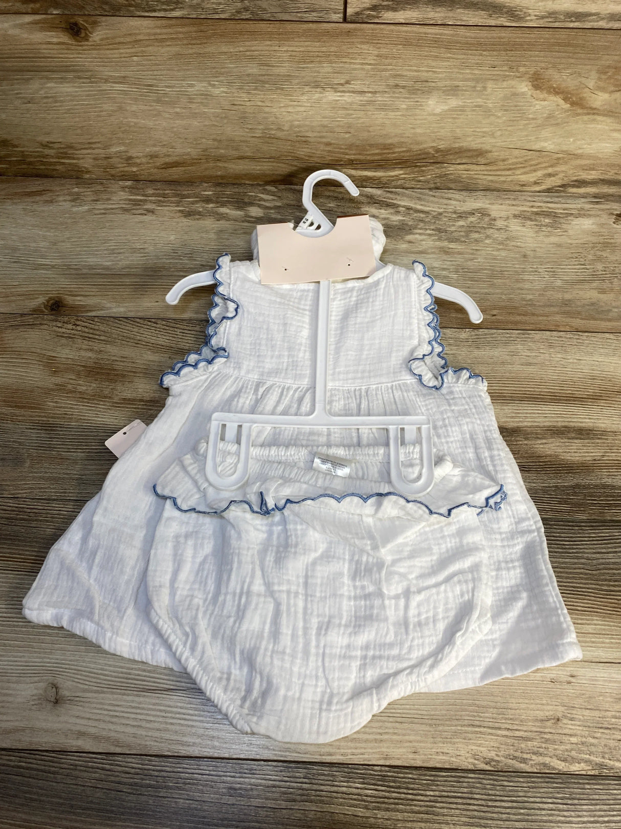 White baby dress and bloomers set with blue trim on wooden background, gently used kids clothes