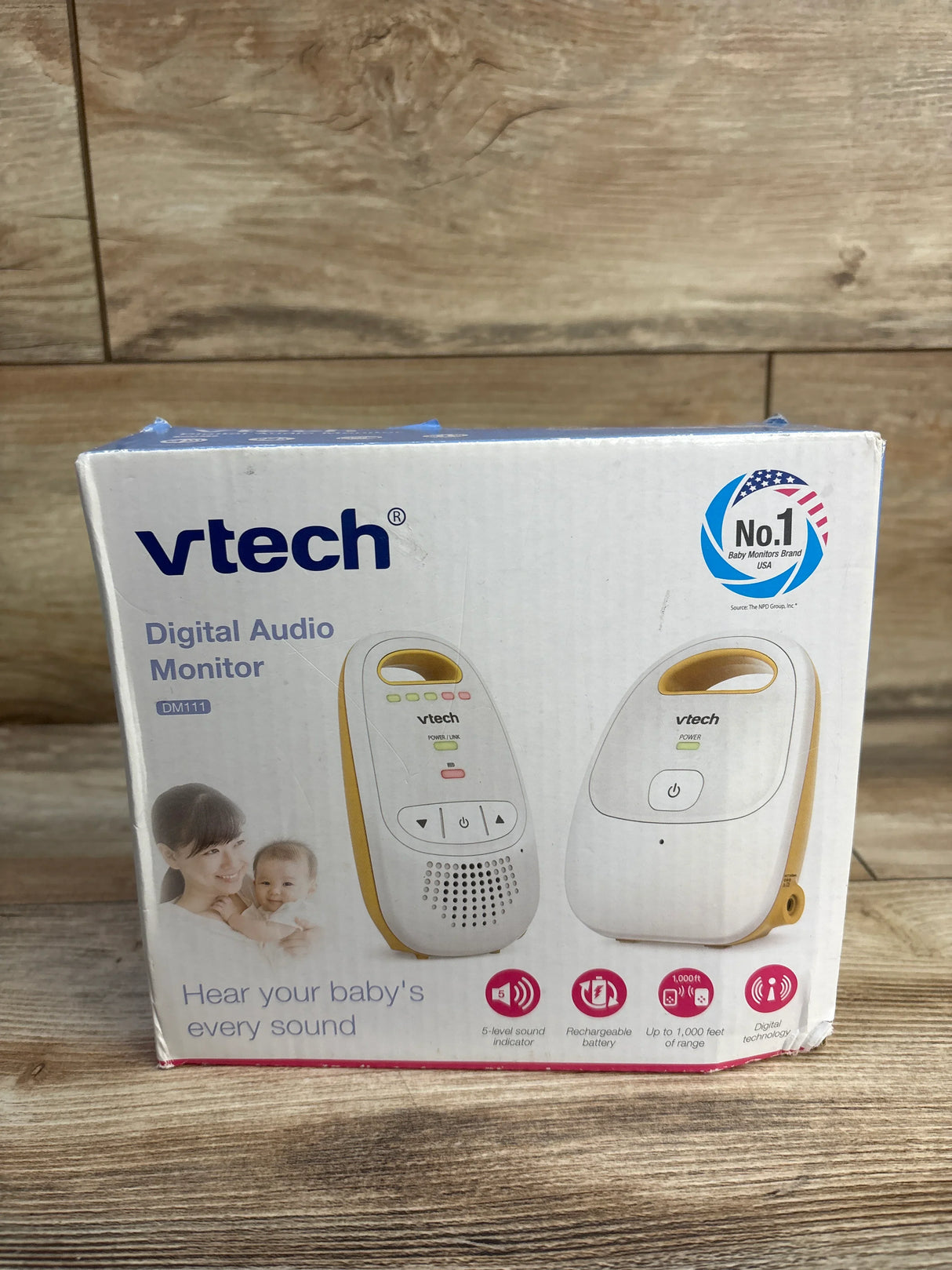 Front of VTech DM111 baby monitor box showing the units and headline Hear your babys every sound on wooden surface