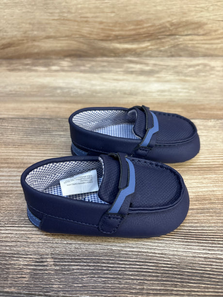 Navy blue baby loafers with textured surface, soft soles, and checkered inner lining on wood background