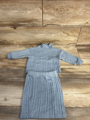 Light blue knit sweater and skirt set on wood floor background