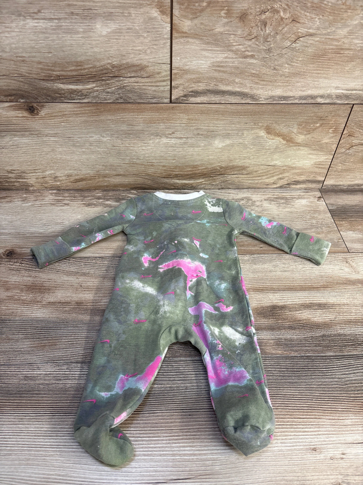 Flat lay of Nike baby footed sleeper, size 3 months, showing green tie-dye with pink and white splashes on wood background