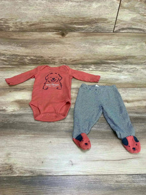 Flat lay of red baby bodysuit and striped footed pants showing dog print on bodysuit and dog faces on feet on wood background
