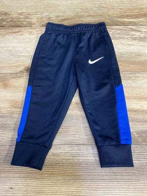 Front view of navy Nike toddler joggers (12 months) showcasing white swoosh, blue side panels, elastic waistband and ribbed ankle cuffs on wooden floor