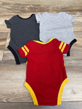 Top view of Wizarding World Harry Potter bodysuits in dark gray, light gray, and red with yellow trim on a wood floor