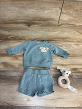 Baby boy outfit with dog appliqué sweater and shorts, plus plush teether toy on wood floor