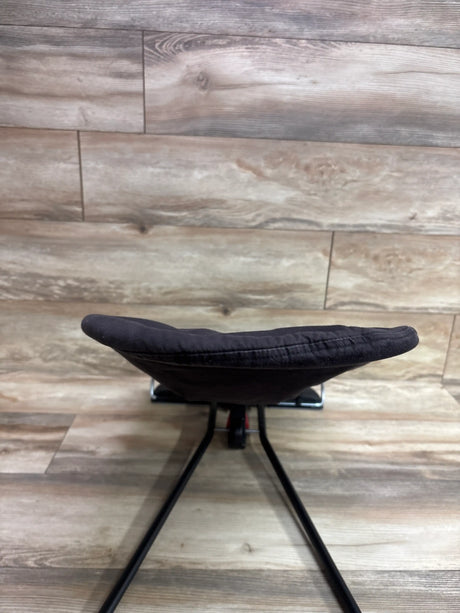 Front view of BabyBjörn Balance Soft Bouncer in Black/Dark Grey showcasing its padded seat and black frame against a wood plank background