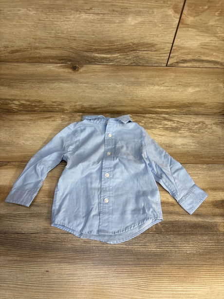Light blue long sleeve button-up baby shirt on wood background