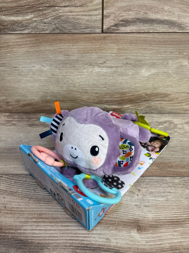 Three-quarter view of purple Fisher-Price monkey stroller toy with teething rings, ribbon tags, and clip on wood surface