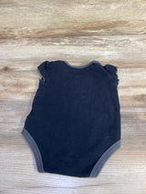 Back view of black baby bodysuit showcasing ruffle cap sleeves and gray trim, laid flat on wood background
