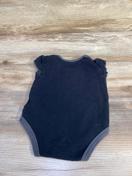 Back view of black baby bodysuit showcasing ruffle cap sleeves and gray trim, laid flat on wood background