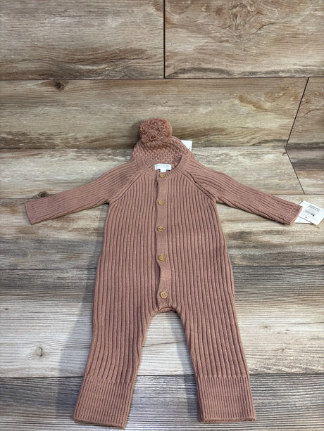 Flat lay of Grayson Mini knit coverall and pom-pom hat set showcasing ribbed texture and wooden buttons on light wood background