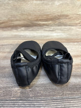 Pair of black leather children's ballet shoes with elastic straps on wood background